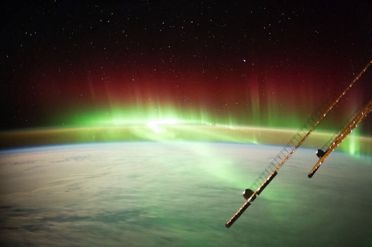 Ribbons of glowing green light curling across Earth's atmosphere.